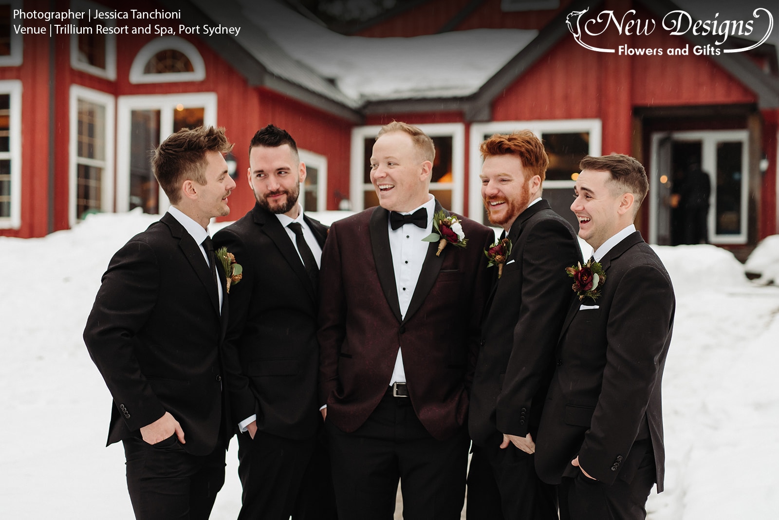 A groom and 4 Groomsmen stand in front of a Red paneled chalet in the winter, with Boutonnieres of Wintergreens, Red Roses and miniature pinecones